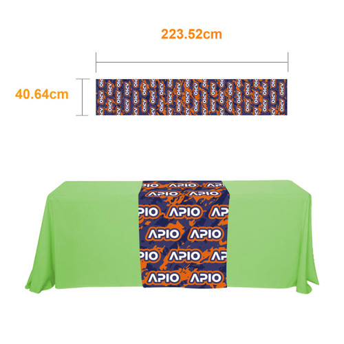 A small table runner in vibrant blue and orange with a branded design, placed on a green tablecloth.