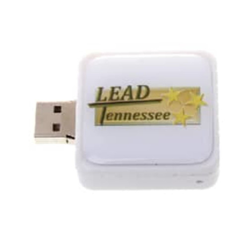 A square white flash drive with a metallic connector and a logo on the surface.