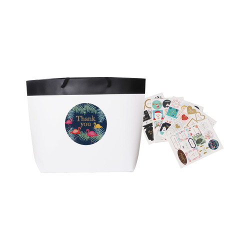 A small black and white boutique paper bag with a black rim and assorted decorative stickers beside it.