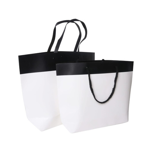 Two small black and white boutique paper bags, featuring a black top section and white lower section with handles.