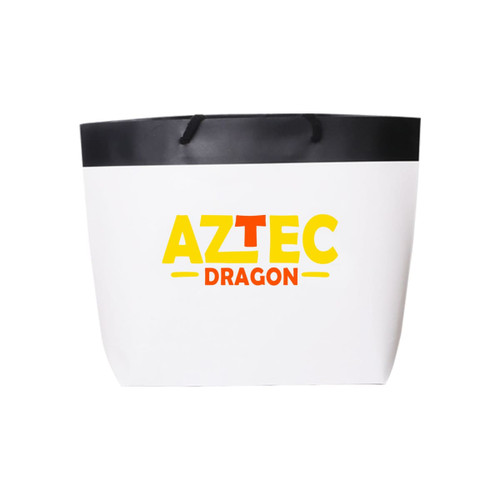 A small black and white boutique paper bag with a black handle and a logo in yellow and red.