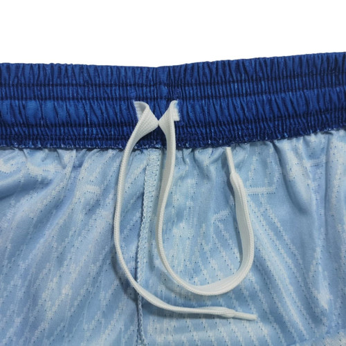 Light blue soccer shorts with a blue waistband and a white drawstring, featuring a textured pattern and a logo.