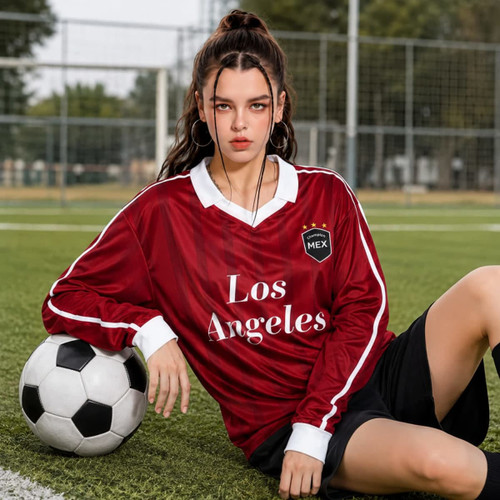 A unisex red football jersey featuring white accents, worn by a model seated beside a soccer ball.