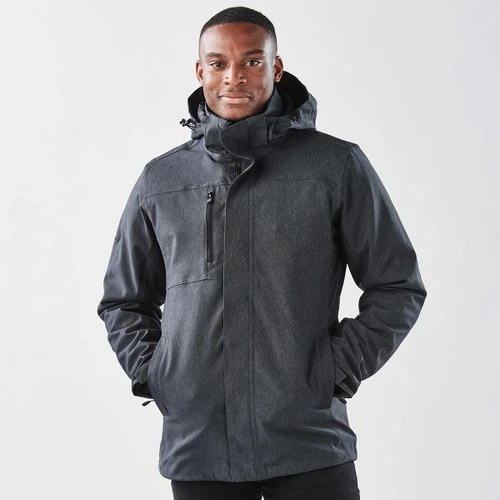A man wearing a black jacket with a hood, featuring a zipper and pockets, against a plain background.