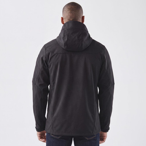 A black softshell jacket with a hood, featuring a logo, shown from the back on a model.