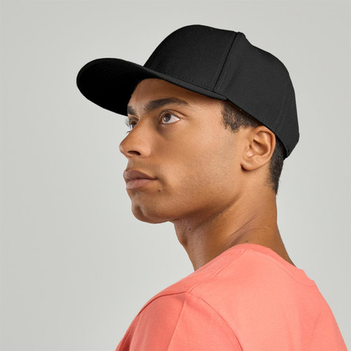 A black cap is worn by a person with short hair, looking upwards against a neutral background.