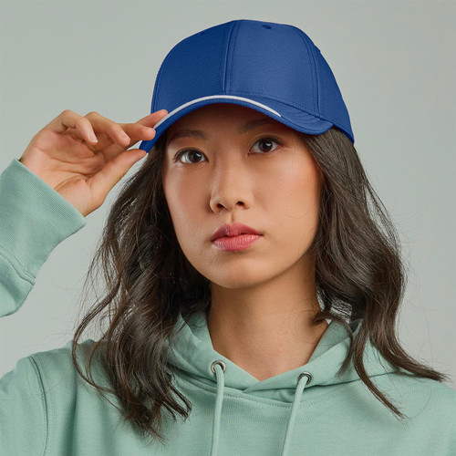 A blue cap with a contrasting brim, being worn by a person with long, wavy hair and a green hoodie.