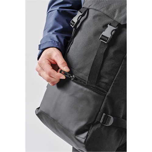 A black backpack with adjustable straps and a zippered pocket being opened by a hand. It features a logo.