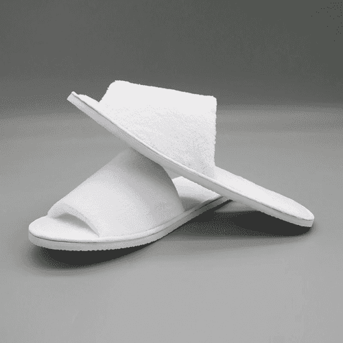 Open toe hotel slippers in white, featuring a soft upper and flat sole, displayed on a grey background.