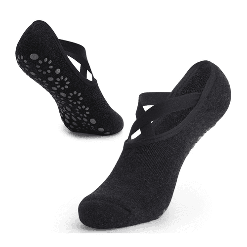 A pair of black yoga socks featuring a cross-strap design and silicone grip dots on the sole.