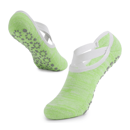 Green yoga socks with a non-slip grip and crossed white straps, showcasing a textured sole for stability.