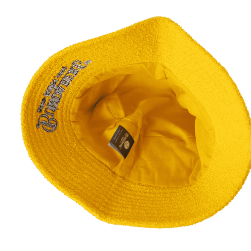 A yellow terry bucket hat with a branded label inside. The interior is fully lined.