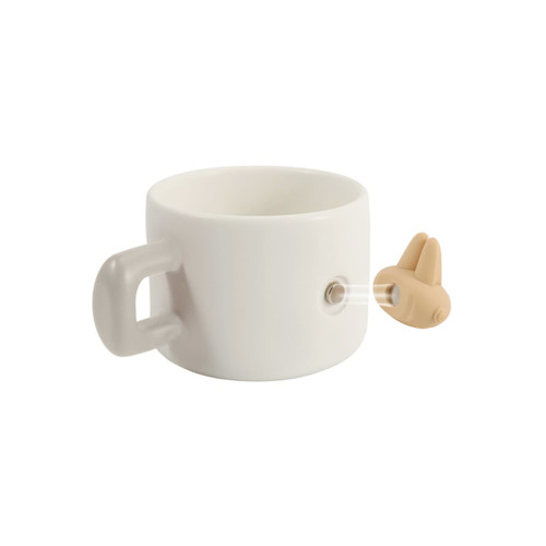 A white ceramic mug with a handle and a magnetic feature on the side, accompanied by a small brown attachment.