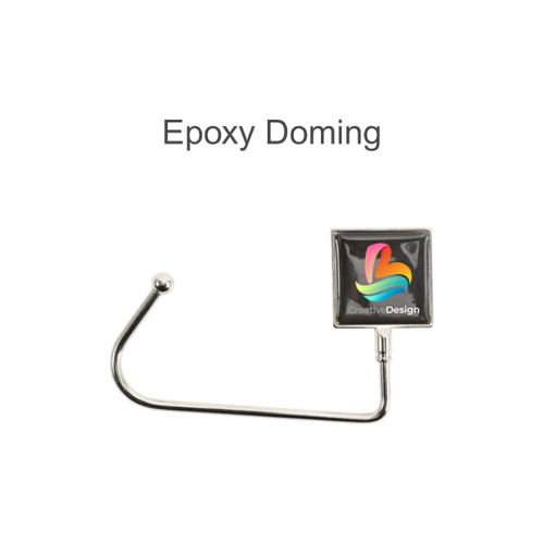 A square silver desk hook with a coloured epoxy domed logo attached at the top.