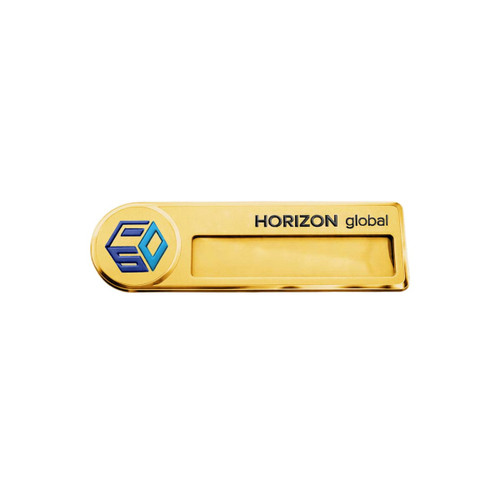 A gold metal name badge with a logo and a clear area for custom text. The design features a sleek rectangular shape.