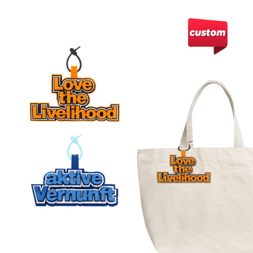 Two custom felt hanging tags in orange and blue, featuring logos, attached to a cream-coloured tote bag.