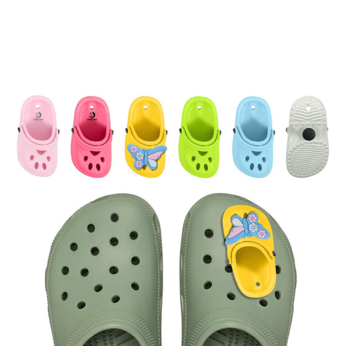 A pair of green clogs with butterfly charms, alongside charms in pink, yellow, blue, and green.