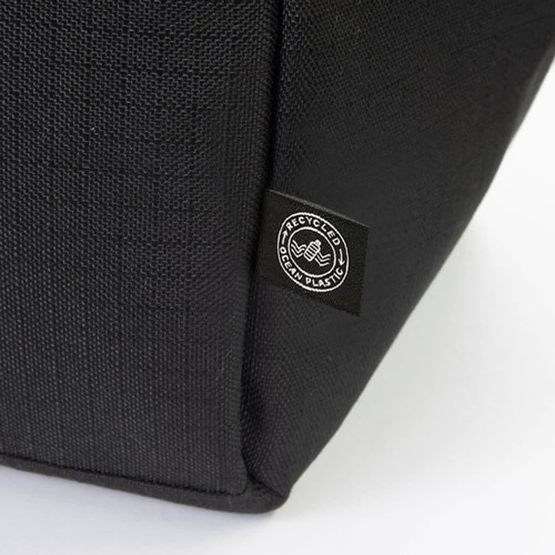 A black cooler bag featuring a logo, made from recycled materials. The textured fabric is visible in the image.