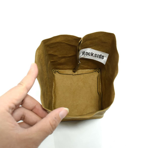 A small brown kraft paper storage bag with a decorative tag inside, being held by a hand.