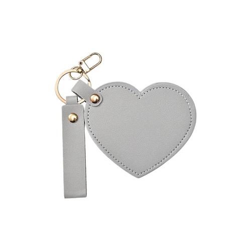 A heart-shaped compact mirror in grey with a keychain attachment, featuring a gold clasp and a wrist strap.