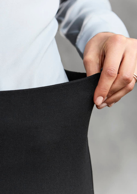 A hand holding the waistband of black women's leggings with a grey background. The leggings feature a smooth texture.