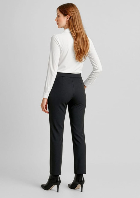 A woman stands wearing mid-rise black pull-on pants and a white long-sleeve top, facing away from the camera.