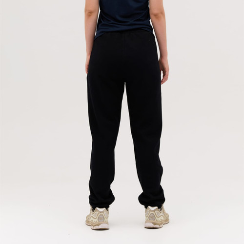 Black track pants featuring a relaxed fit, worn by a person from the back, paired with light-coloured sneakers.