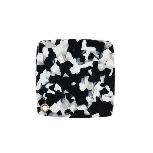 A square acetate vanity mirror featuring a black and white speckled design with a small gold accent.