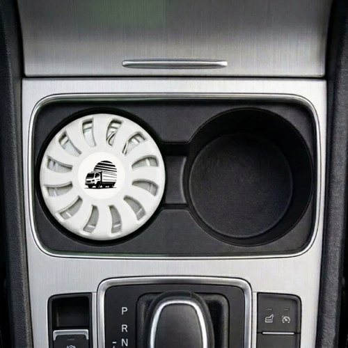 A white air freshener sits in a car cup holder, featuring a circular design and a logo.