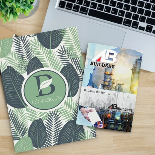 A large notebook with a leaf design in green and cream, alongside a brochure for a construction company.