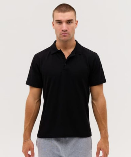 A black polo shirt displayed on a male model, featuring a collar and short sleeves. The shirt has a logo.