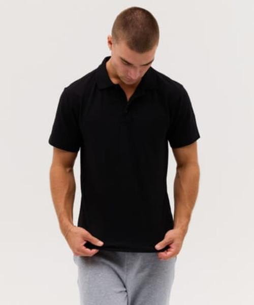 A black polo shirt is displayed, featuring a classic collar and short sleeves. The model wears grey sweatpants.