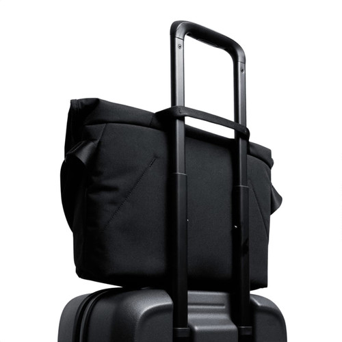 A black messenger bag positioned on top of a wheeled suitcase, featuring a retractable handle.