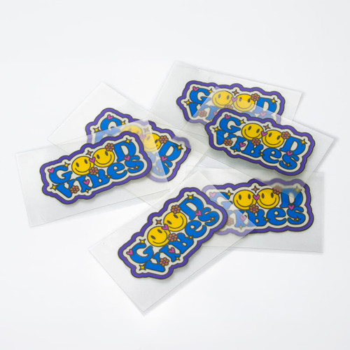 Colourful stickers featuring smiling faces and playful text, with a glossy finish, presented on a white background.