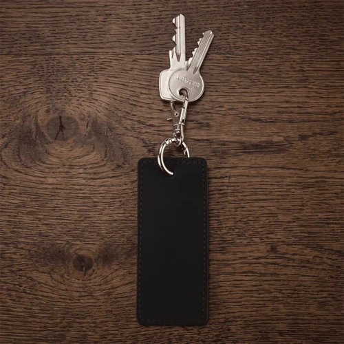 A black rectangular keychain attached to several metal keys on a wooden surface.
