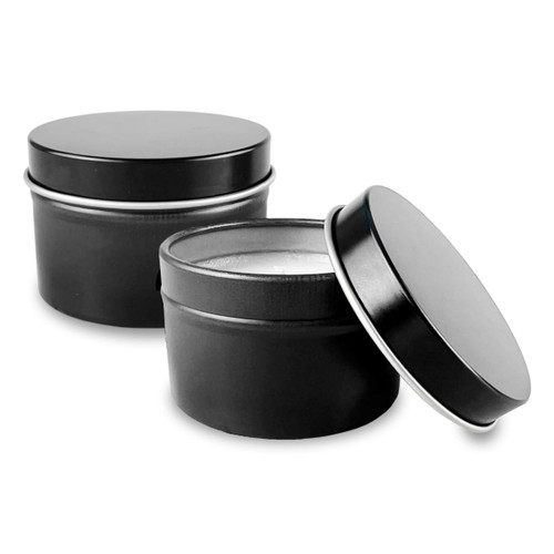 Two black tin candles with circular lids, one slightly open to reveal the wax inside.