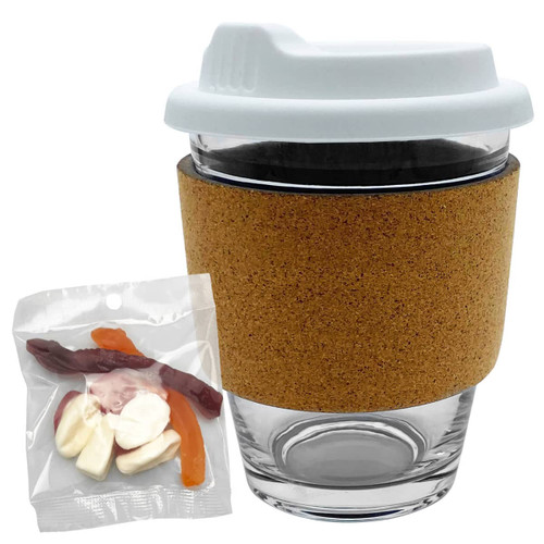 A glass coffee cup with a cork band and a white lid, alongside a bag of mixed lollies in various colours.