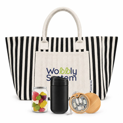 A striped tote bag in black and white with a cream pocket, a jar of colourful sweets, a black drink container, and a wooden item.