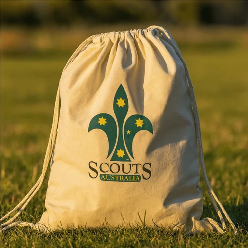 A calico drawstring bag in cream colour featuring a green logo with a fleur-de-lis and stars.