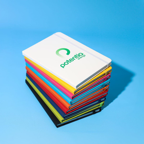 A stack of A5 notebooks in various bright colours, featuring a logo on the white cover at the top.
