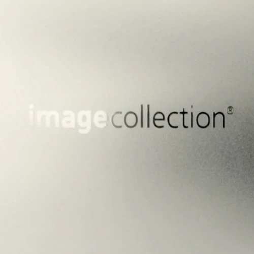 A sleek, metallic silver business card holder features a subtle logo and a refined, glossy finish.