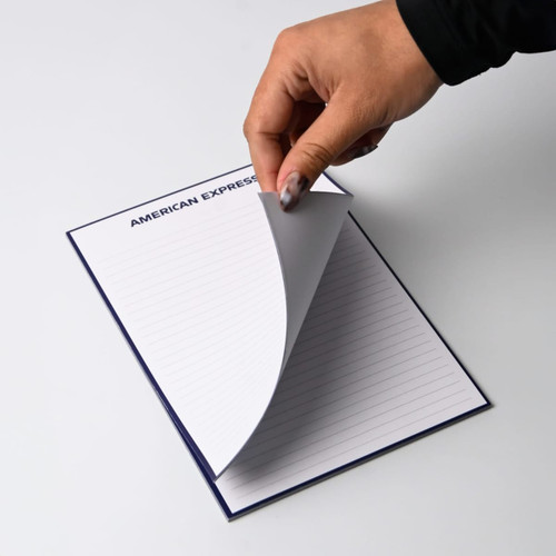 A5 note pad with a navy cover, featuring plain lined leaves being turned over, and a logo on the top.
