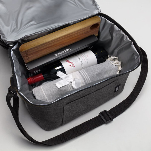 A grey cooler bag with a wine bottle, a wooden wine opener, and a rolled-up blanket inside. It has a logo.