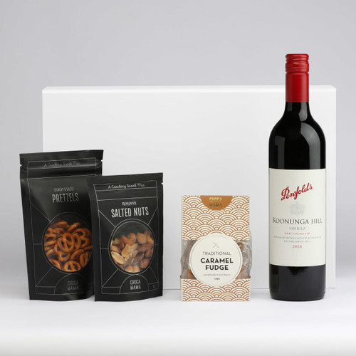 A drink bottle of red wine accompanied by packets of salted nuts, pretzels, and caramel fudge. All items are elegantly arranged.
