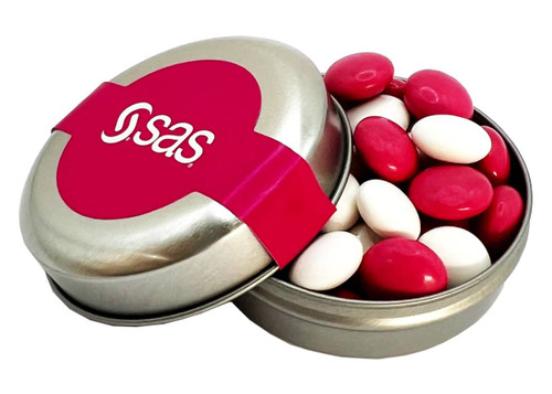 A silver tin container with a lid, filled with red and white chocolate-coated beans and featuring a logo.