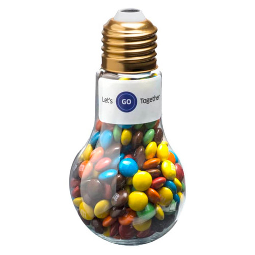 A light bulb-shaped container filled with colourful M&Ms, featuring a golden cap and a label.