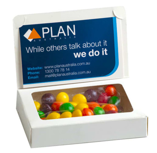 A white box containing colourful Skittles candies, featuring a branding logo on the lid.