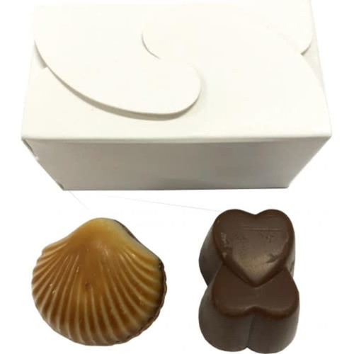 A white box contains two chocolates: a brown heart-shaped piece and a caramel sea shell-shaped chocolate.