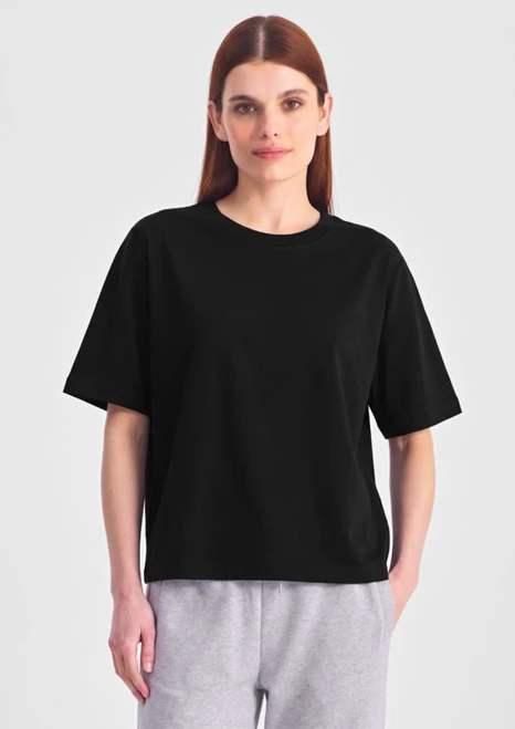 A black box tee in a relaxed fit, featuring short sleeves. The model wears it with grey bottoms.