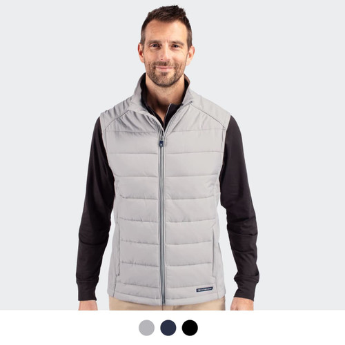 A man in a light grey quilted vest stands against a plain background. The vest features a branding logo.